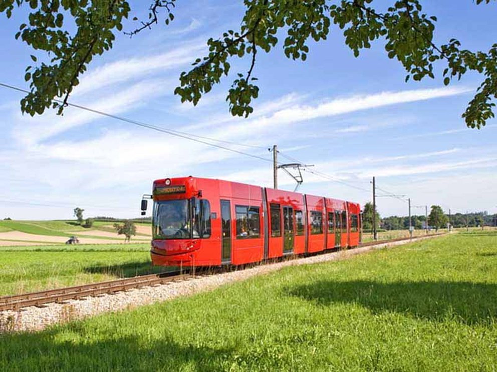 Die neue Traunseebahn fährt an saftigen Wiesen vorbei.