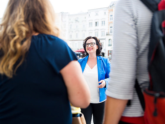 Stadtführerin erzählt ihrer Gruppe eine spannende Geschichte in den Straßen von Linz.