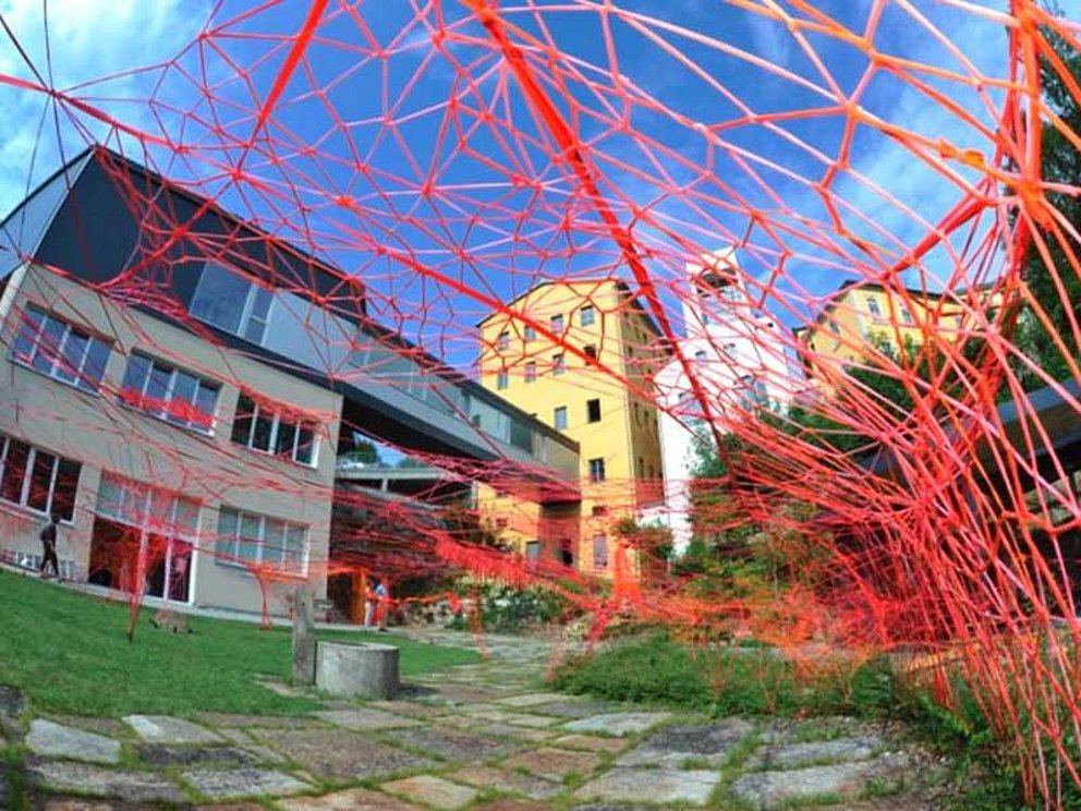 Blick durch rote Fäden auf das Webereimuseum in Haslach