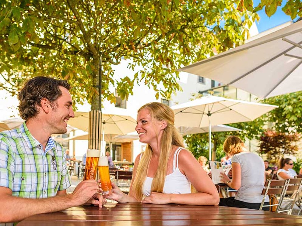 Paar trinkt Bier in Gastgarten der Braucommune Freistadt