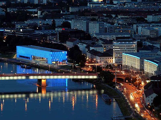 bei Nacht sind in Linz das LENTOS Kunstmuseun und Nibelungenbrücke hell erleuchtet.