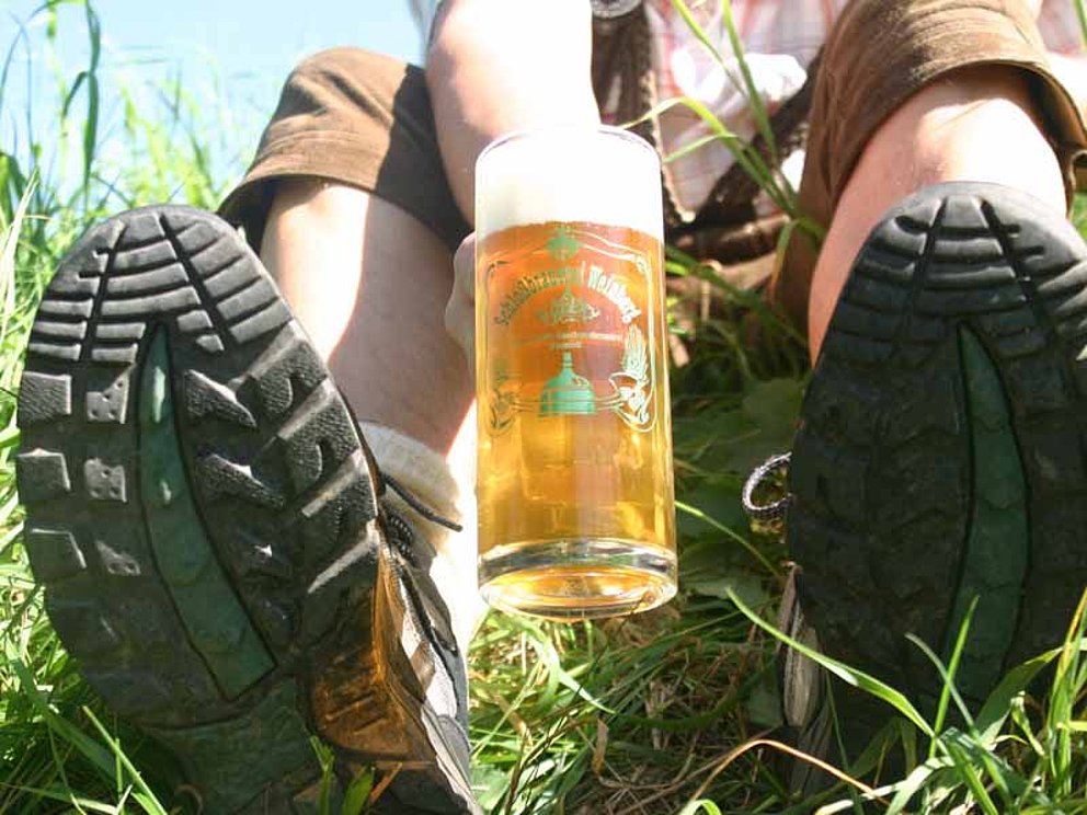 Wanderrast mit einem schaumgekrönten Glas Bier im Grünen