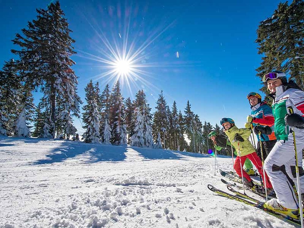 Skifahrer warten am Pistenrand in der Sonne im Skigebiet Hochficht