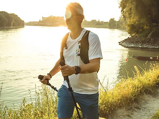 Wanderer mit Stöcken auf einem Weg am Donauufer