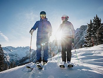 2 Skifahrer im Tiefschnee, im Hintergrund die Sonne