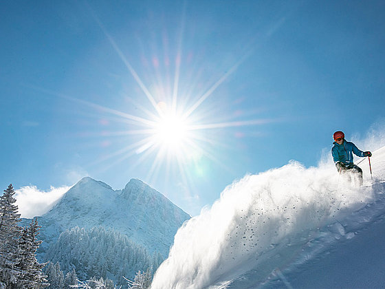 Skifahrer im Tiefschnee bei strahlendem Sonnenschein