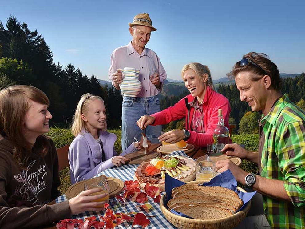 Familie zu Tisch mit köstlichem Bauernschmaus im Freien