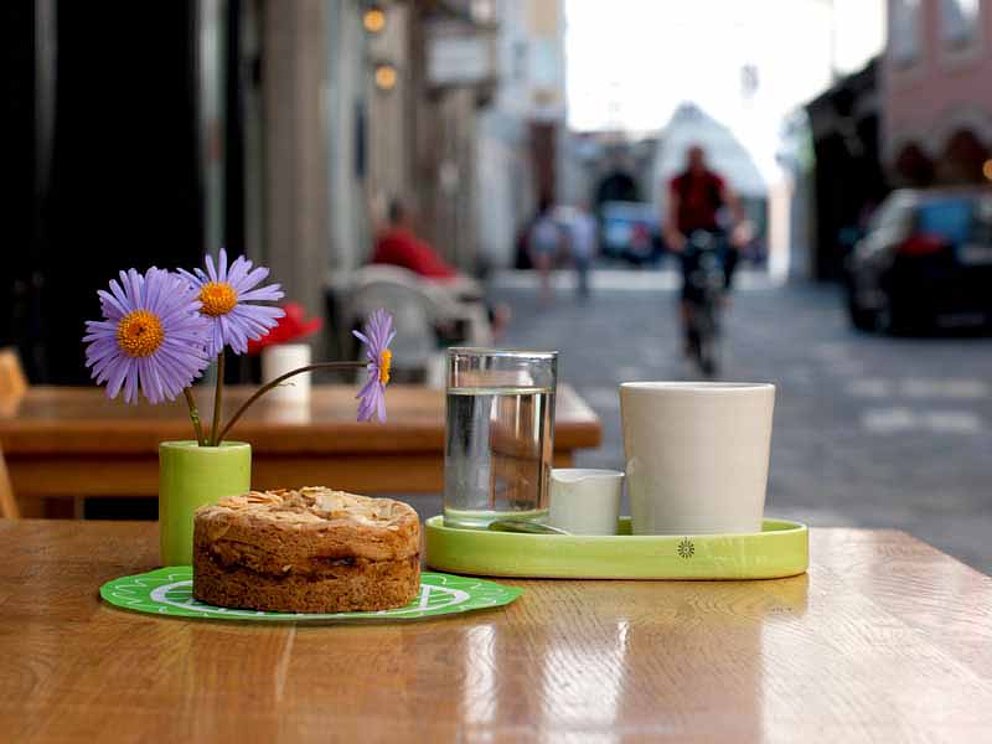 Am Kaffeehaustisch im Freien stehen eine Tasse Kaffee und ein Stück Linzer Torte
