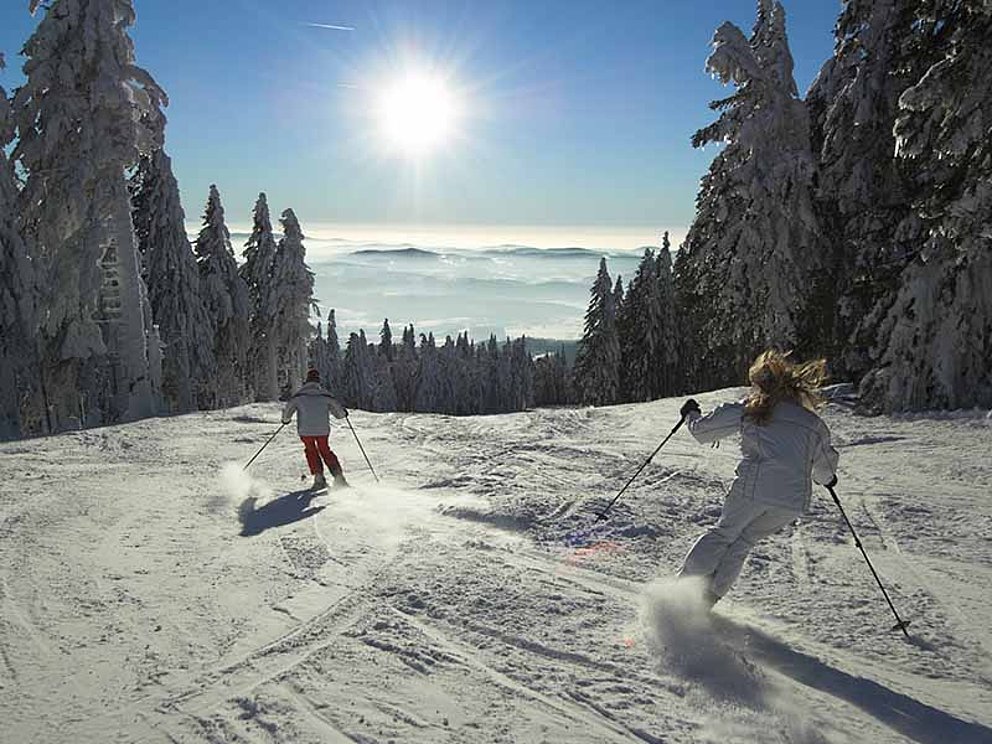 Zwei Skifahrer auf der Hochfichtpiste bei Sonnenschein