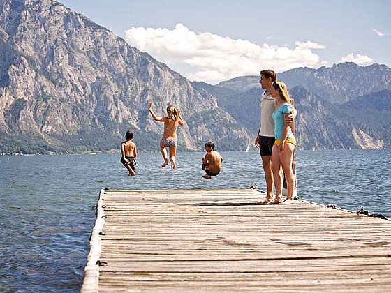 Kinder springen in den Traunsee im Sommerurlaub im Salzkammergut