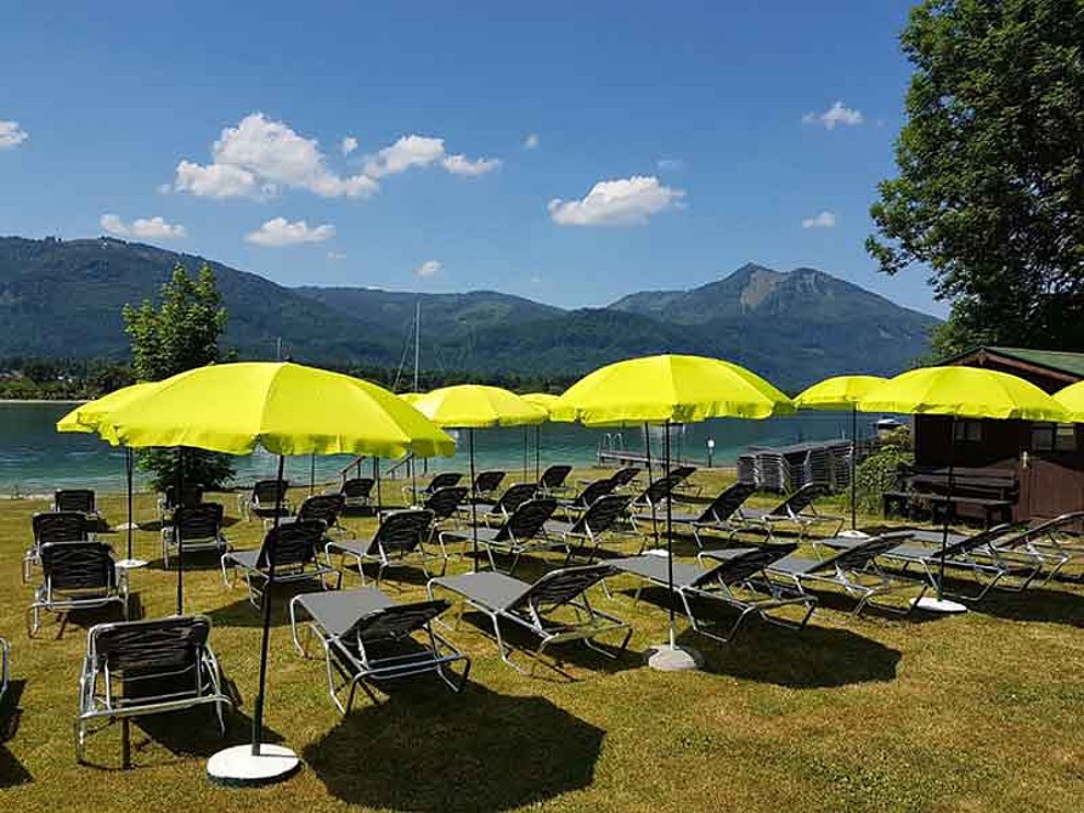 Badestrand mit Sonnenschirmen und Liegen am Wolfgangsee beim Hotel Försterhof