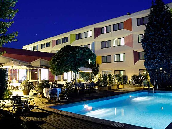 Nachtaufnahme vom Hotelgarten mit Pool im Ibis Styles Linz