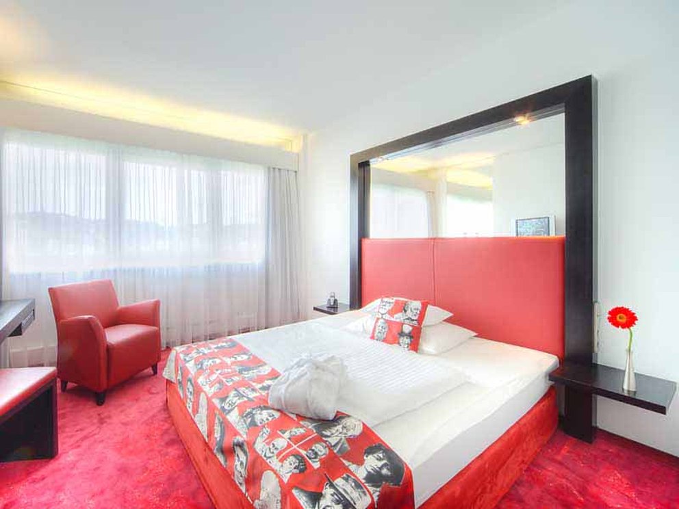 Doppelzimmer Superiro im ARCOTEL Nike in Linz. Das Zimmer ist mit Teppichboden, großem Doppelbett, Fauteuil und Schreibtisch ausgestattet.