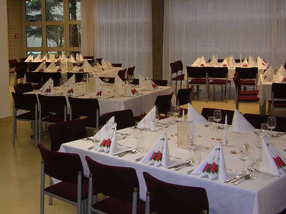 Restaurant im Hotel Sommerhaus in Linz. Am Bild sind mehrere Tischgruppen für je 10 Personen, die gedeckt sind.