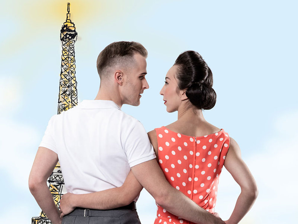 Ein junges Paar vor dem Eiffelturm.