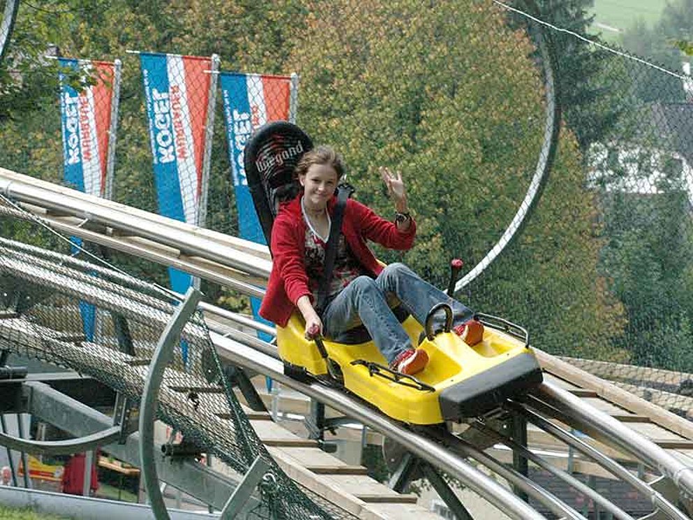 Mädchen fährt talwärts mit dem Alpine Coaster am Wurbauerkogel