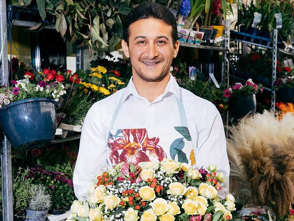 Floristiker hält einen prächtig gebundenen Blumenstrauß in seinem Laden.