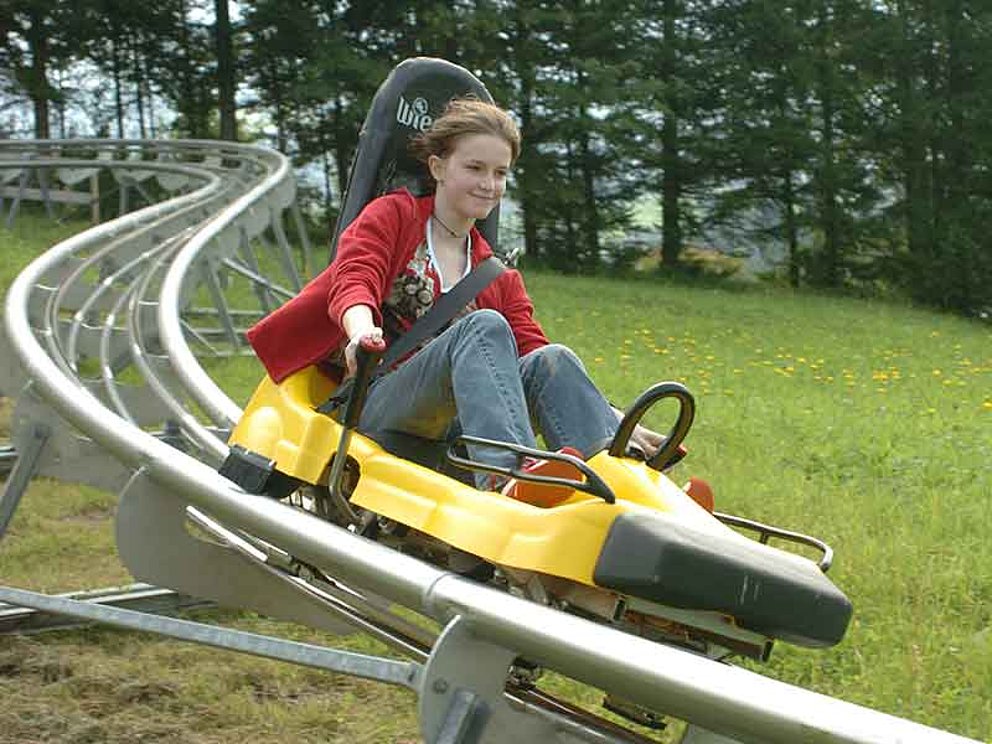 Mädchen fährt mit dem Alpine Coaster vom Wurbauerkogel ins Tal