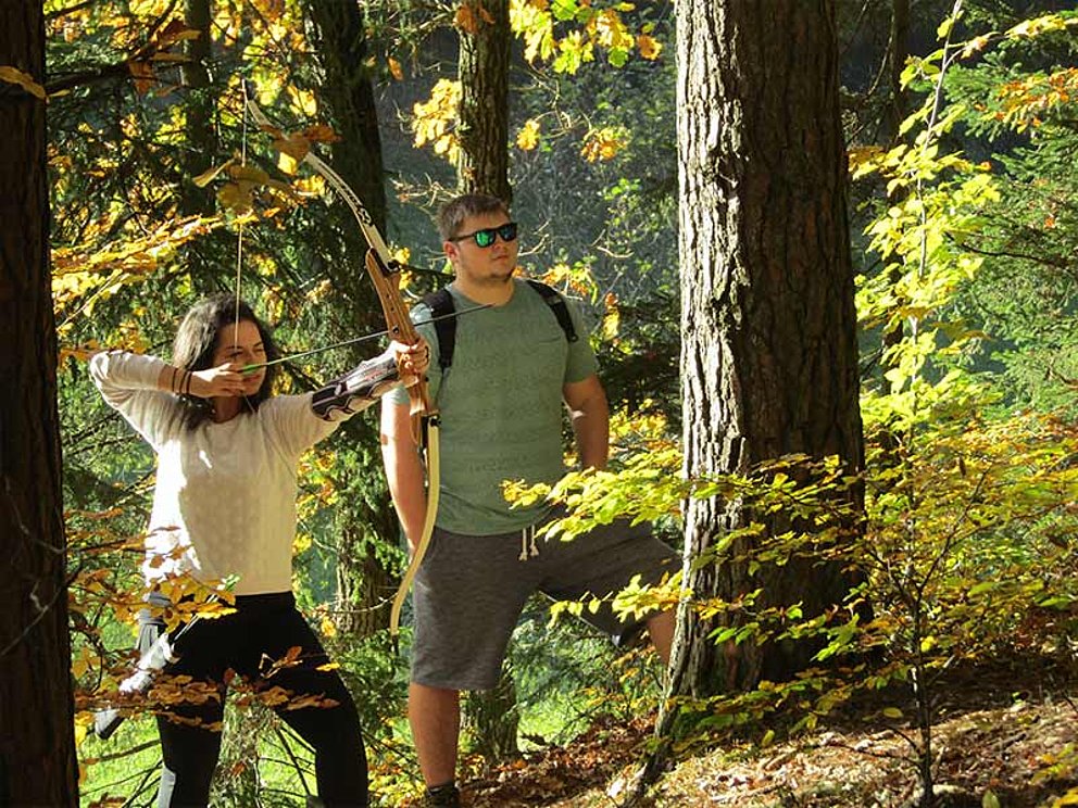 Bogenschützen im Wald mit gespanntem Bogen