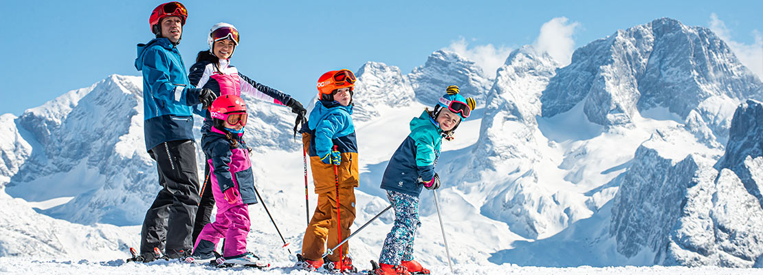 eine Familie auf Skiern vor dem Dachstein