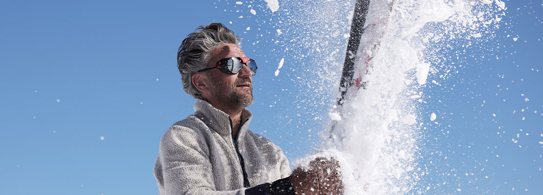 ein Mann in einer Schneestaubwolke, blauer Himmel im Hintergrund