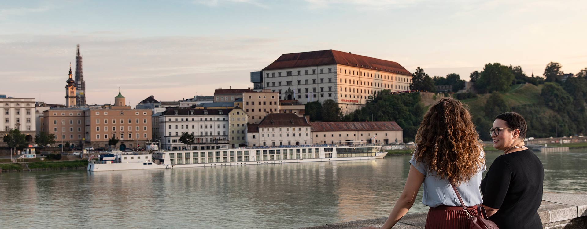 2 Damen schauen über die Donau in Richtung Linzer Altstadt mit dem Schloss